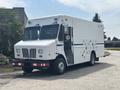 2011 Workhorse W62 box truck with a white exterior and blue stripe parked on a roadway with side compartments and multiple doors