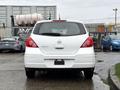 A white 2012 Nissan Versa viewed from the rear showcasing its hatchback design and the brand logo on the back