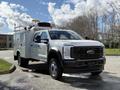 A 2024 Ford F-550 work truck with a silver utility body equipped with storage compartments and tools on the roof