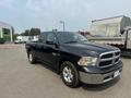 A black 2015 RAM 1500 pickup truck parked with chrome accents and a spacious cab visible from the side angle