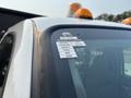 A 2009 Ford F-450 Super Duty featuring an orange beacon light on the roof and a sticker with monthly certification details on the driver's side window