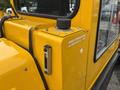 A yellow hydraulic oil reservoir with a black cap and a small gauge located on a Bombardier SW48 vehicle