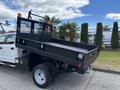 A black 2017 Ford F-550 with a flatbed and a safety railing is parked, showing its dual rear wheels and work-ready features