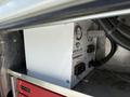 A white Vanair air start engine equipment with a pressure gauge and various control switches inside a storage compartment of a vehicle