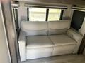 A light-colored sofa with a contemporary design featuring a smooth surface and plush cushions located within a recreational vehicle