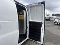 A 2022 GMC Savana with its side door open revealing a spacious cargo area and a sign that reads Is Your Load Secure