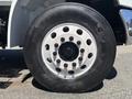 A close-up view of a black tire mounted on a white rim with multiple circular holes showcasing the brand name Firestone and the model F567