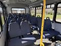 A 2017 Chevrolet Express interior featuring rows of blue upholstered seats with seat belts and a vacant aisle running through the center