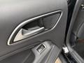Close-up view of the door handle and controls on the interior of a 2016 Mercedes-Benz GLA-250 featuring textured black material and metallic accents