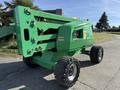 A green 2015 JLG 450AJ scissor lift with large tires and extended platform features a control panel on the side and a company logo on the front