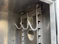 A metal rack with three hooks installed inside a compartment of a 2005 Freightliner M2 106 truck
