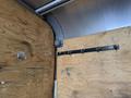 A black metal hook strip with multiple hooks mounted on wooden panels inside a vehicle cargo area