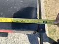 A person measuring the edge of a black metal surface with a yellow tape measure marked in feet and inches