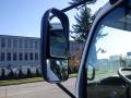 A side mirror of a 2015 Hino 195 truck reflecting the view along a road