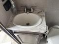 A white sink with a curved bowl set in a marble countertop with two metal faucet handles and a drain visible