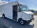 A 2012 Ford Econoline delivery truck with a white exterior and large side doors for cargo access