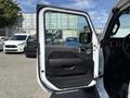 A 2021 Jeep Wrangler with the front door open showing the interior details such as the door panel and controls