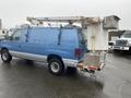 A blue 2009 Ford Econoline van with a white bucket lift attached to the roof and a platform at the rear for work at height