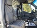 Interior view of a 2024 Mercedes-Benz Sprinter 2500 showing two front seats with seatbelts and a central console between them