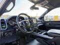 Interior of a 2023 RAM 3500 featuring a black steering wheel with controls a digital display dashboard and a large center console with storage space