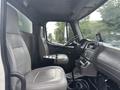 Interior of a 2006 Freightliner M2 106 featuring two grey seats a steering wheel and a gear shift with dashboard controls visible