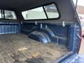A 2006 Dodge Ram 2500 truck bed with a cap featuring a textured interior and a wooden floor showing signs of wear and dirt