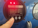A close-up of a tachometer display showing 788 RPM with buttons for hours clear dim and a finger pressing one of the buttons on a blue dashboard panel