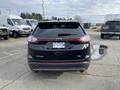 A black 2017 Ford Edge seen from the rear with its emblem and dual exhaust pipes visible