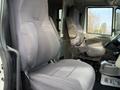Interior view of a 2013 International Durastar 4300 showing two grey cloth seats with a central console and dashboard elements visible