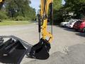 A 2022 Caterpillar 306 excavator with a black bucket attachment is positioned upright showcasing its hydraulic arm and mechanical components