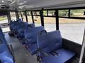 Interior of a 2020 Chevrolet Express bus featuring blue upholstered seats with seatbelts and a spacious layout for passengers