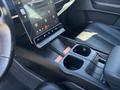 Interior view of a 2023 Fisker Ocean showcasing the central touchscreen display and the console area with cup holders and gear shift panel