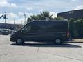 A black 2025 Ford Transit T-350 van parked with its side view visible and wheels partially turned