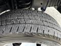 Close-up of a tire from a 2014 Ford E-350 showcasing its tread pattern with visible wear and small debris embedded in the rubber surface