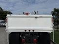 A white 2008 International 4300 dump truck is shown from the rear featuring a flatbed with raised sides and chains attached to the tailgate. The truck has reflective lights and a hitch at the bottom