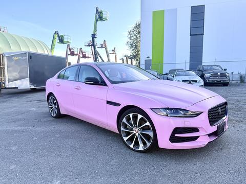 A pink 2020 Jaguar XE with a sleek design featuring a prominent grille and stylish wheels positioned at an angle