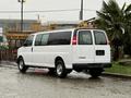 A white 2021 Chevrolet Express van is parked with its sliding side door open and visible rear windows