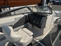 A 2013 Larson 238 boat interior featuring a steering console and a single captain's seat in light colors with a simple design