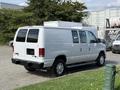 A white 2013 Ford Econoline van parked with a sliding side door and a rear cargo space featuring a metal mesh divider