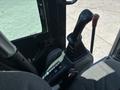 Control joystick and buttons of a 2010 Bobcat E80 excavator cabin with grey fabric seat and red parking brake lever