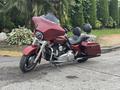 A 2009 Harley-Davidson Road King motorcycle in a deep red color featuring a large windshield saddlebags and a classic cruiser design with two seats