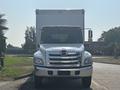 A white 2012 Hino 338 box truck facing forward with a shiny chrome grille and headlights visible