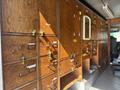 A wooden service cabinet with multiple drawers and compartments featuring metal handles and locks inside a vehicle