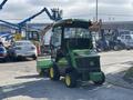 A green and yellow 2021 John Deere 1575 utility tractor with a cab and mowing deck in the foreground