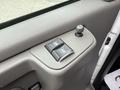 A gray door panel from a 2004 Chevrolet Express featuring power window controls and a manual window crank