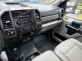 Interior view of a 2018 Ford F-550 featuring a modern dashboard with controls and a gear shift along with light grey seats and a textured floor mat