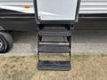 Four black metal steps leading up to a trailer door with a silver and black exterior design