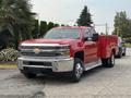 A red 2015 Chevrolet Silverado 3500HD truck with a chrome front grille and a service body on the back parked on a driveway