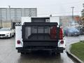 A white 2000 Ford F-450 with a black meshbed and red equipment in the cargo area is parked upright facing the viewer