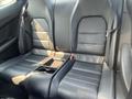 Black leather back seats of a 2013 Mercedes-Benz C-Class with a central armrest and cup holders visible between the seats
